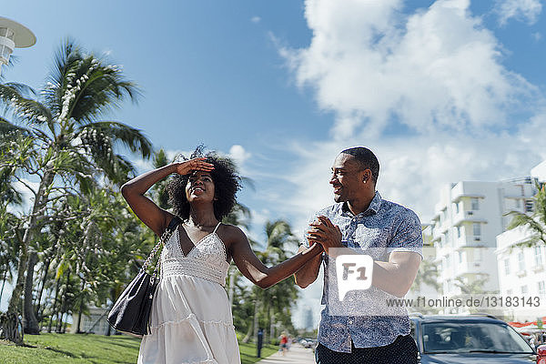 USA  Florida  Miami Beach  glückliches junges Paar geht gemeinsam die Straße entlang