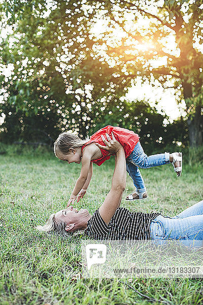Happy mother playing with daughter on meadow
