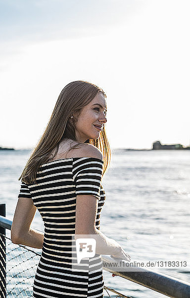 USA  New York  Brooklyn  young woman wearing striped dress standing in front of East River