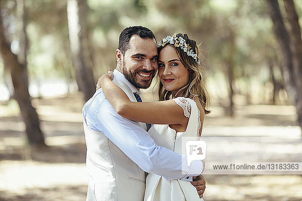 Portrait of happy bridal couple standing head to head in pine forest