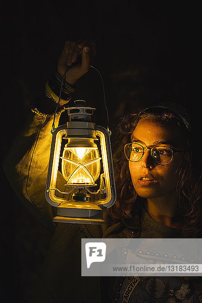 Young woman holding storm lantern in the dark