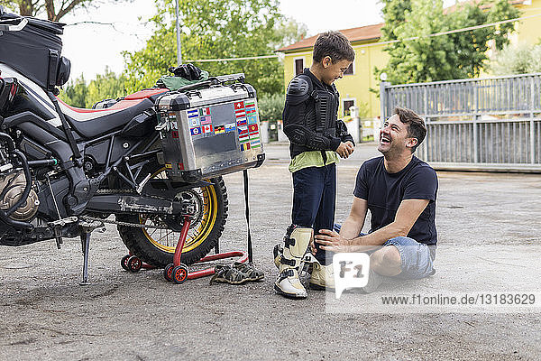 Happy father and son next to a motorbike