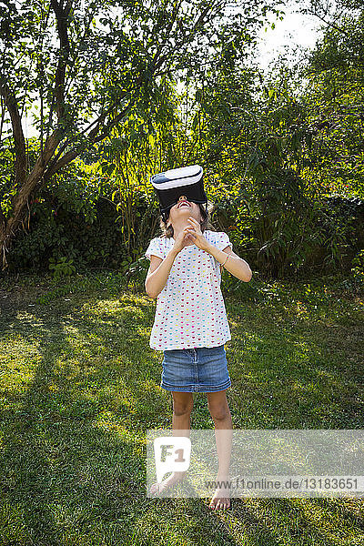 Kleines Mädchen mit Virtual-Reality-Brille im Garten