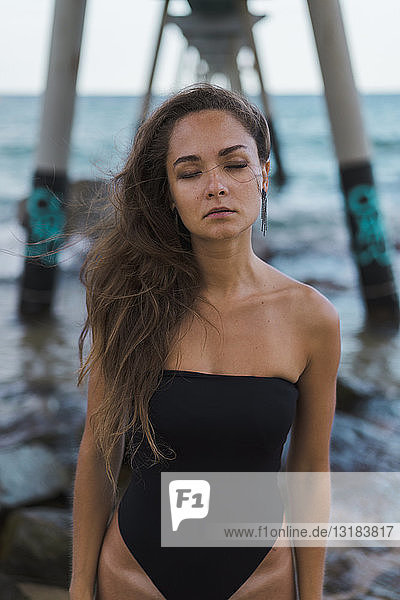 Hübsche junge Frau mit geschlossenen Augen im Badeanzug an der Strandpromenade