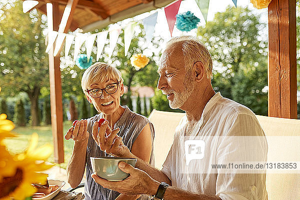 Älteres Ehepaar isst Tomaten auf einer Gartenparty