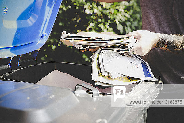 Tätowierter Mann beim Recycling von Altpapier in der Papierbank  Teilansicht