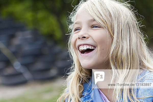 Porträt eines lachenden blonden Mädchens im Freien