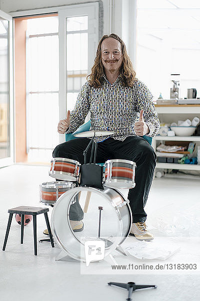 Portrait of confident man sitting at toy drums