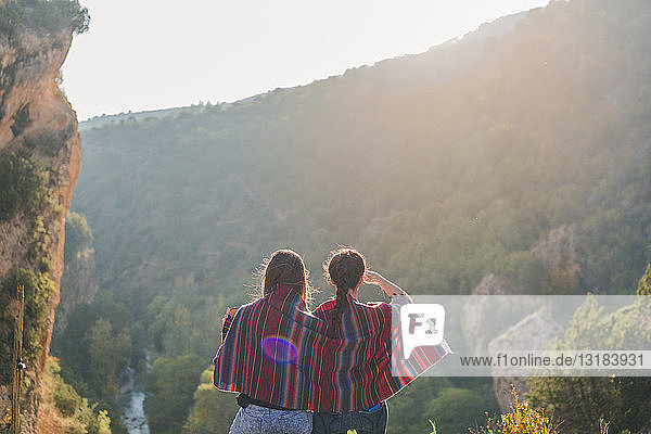Spain  Alquezar  rear view of two young women on a hiking trip sharing a blanket