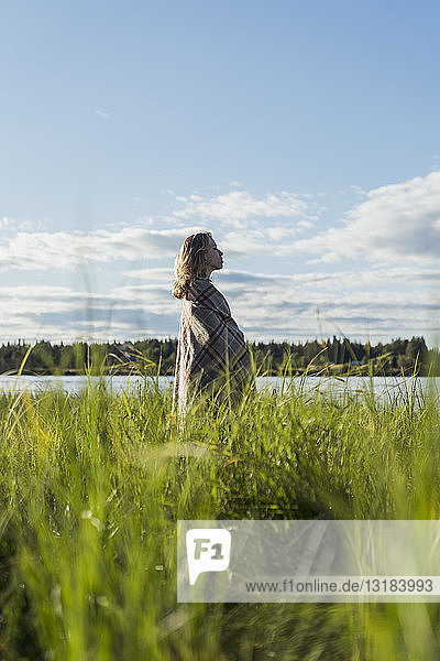 Finnland  Lappland  Frau in eine Decke gewickelt am Seeufer stehend