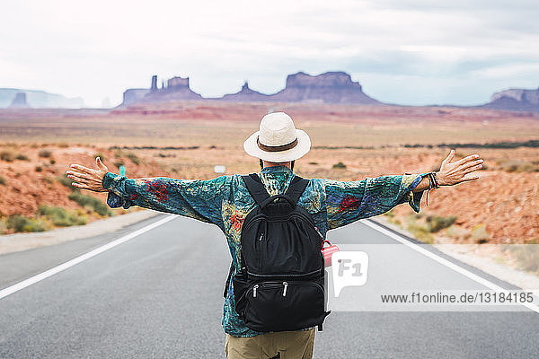 USA  Utah  Mann mit Rucksack steht auf der Straße zum Monument Valley