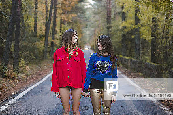 Two young women standing on country road facing each other