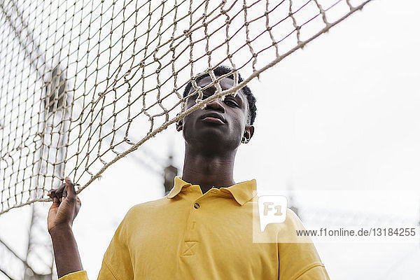 Porträt eines jungen schwarzen Mannes am Volleyballnetz stehend