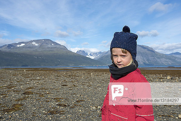 Norwegen  Mädchen mit Pudelmütze und roter Jacke am Strand  Lyngenfjord