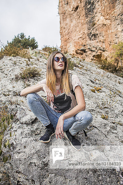 Junge Frau auf einer Wanderung auf einem Felsen sitzend