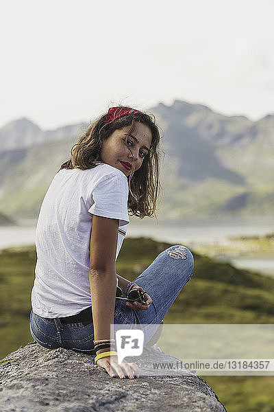 Junge Frau sitzt auf einem Felsen und schaut auf die Aussicht. Lappland  Norwegen
