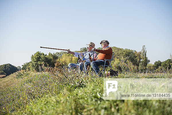 Two old friends sitting in the fields  drinking beer  pointing with walking stick