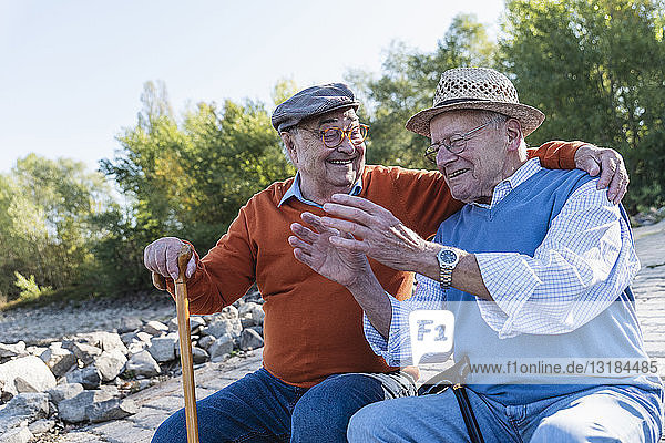 Two old friends sitting by the riverside  having fun