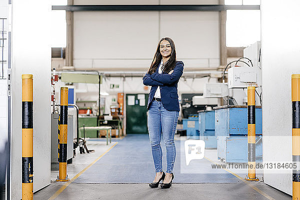 Confident woman working in high tech enterprise  standing in factory workshop with arms crossed