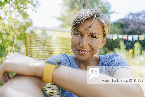 Portrait of smiling woman sitting in garden on chair