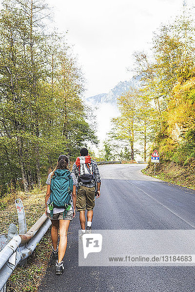 Italy  Massa  rear view of young couple walking on asphalt road in the Alpi Apuane mountains