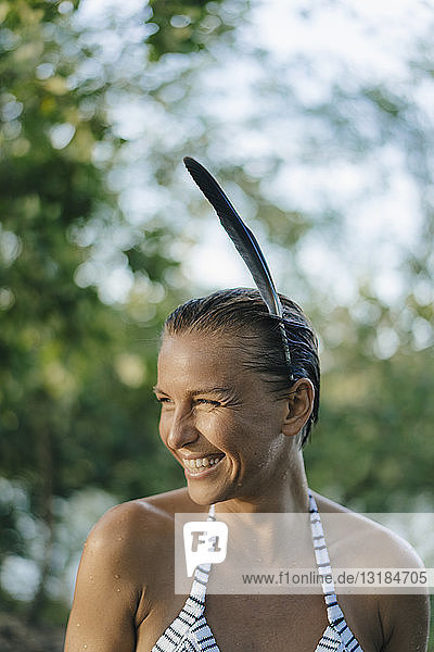 Bildnis einer glücklichen Frau mit nassem Haar  die eine Feder im Haar trägt