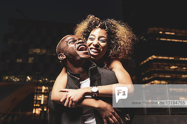 Lachendes junges Paar amüsiert sich nachts in der Stadt