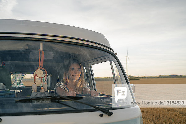 Lächelnde junge Frau fährt Wohnmobil in ländlicher Landschaft
