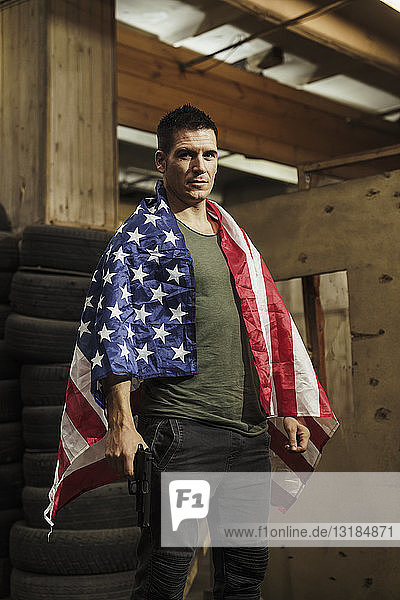 Portrait of man wearing American flag holding a gun