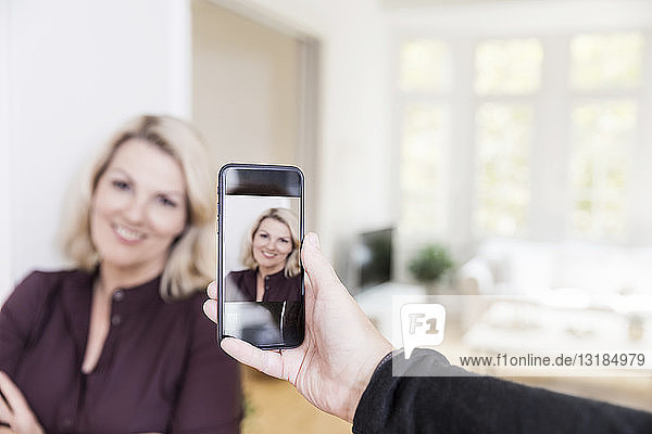 Man taking photo of woman with smartphone at home  close-up