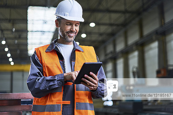 Smiling man using tablet in factory