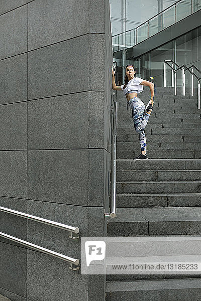 Young woman doing stretching exercise on stairs