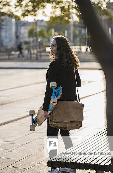 Young woman with longboard in the city on the move