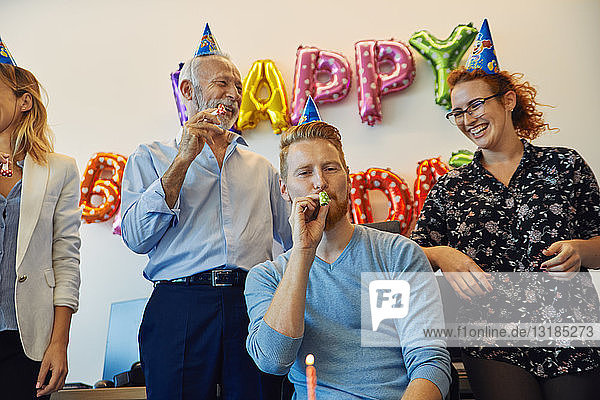 Kollegen feiern Geburtstag im Amt mit Partyblower und Partyhüten