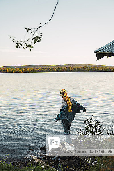 Junge Frau an einem See  auf einem Brett balancierend