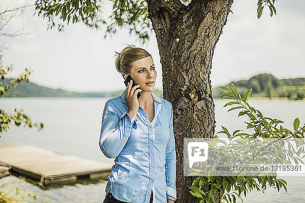 Frau mit Handy an einem See