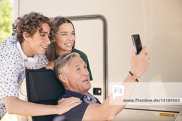 Älterer Mann nimmt sich mit Enkelkindern per Smartphone im Wohnwagen mit