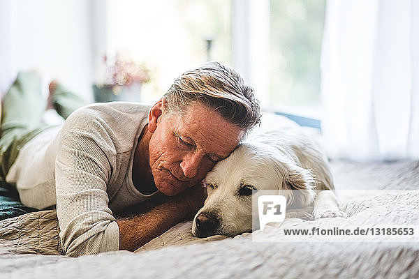 Retired man sleeping with dog comfortably on bed at home