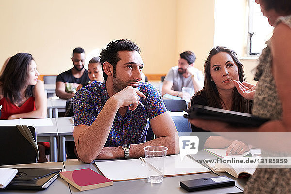 Männliche und weibliche Studenten sehen den Lehrer beim Erklären im Klassenzimmer