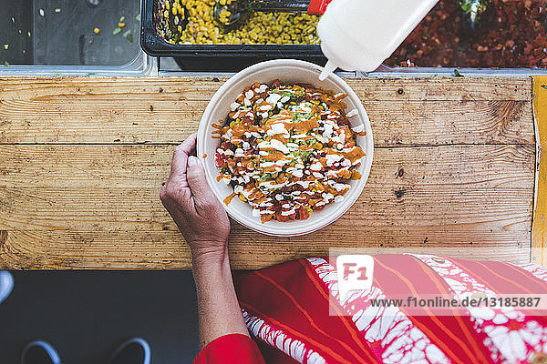 Midsection of female customer with fresh Tex-Mex in bowl at food truck