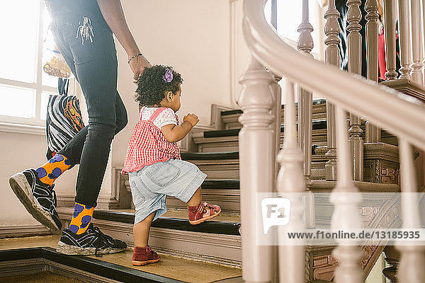 Kleines Mädchen hält Hand des Vaters beim Treppensteigen in der Wohnung