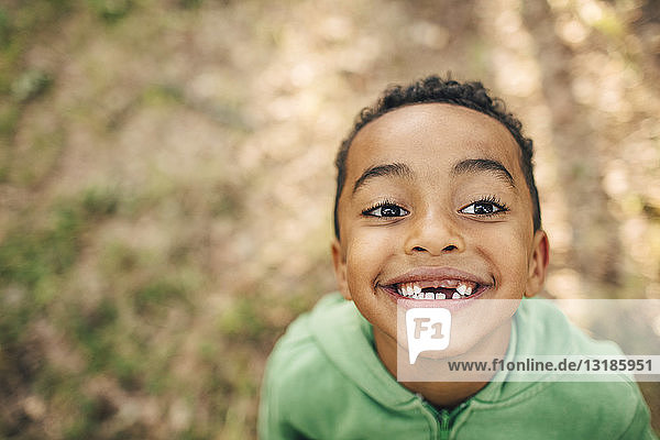 Hochwinkelaufnahme eines lächelnden Jungen mit Zahnlücke im Park