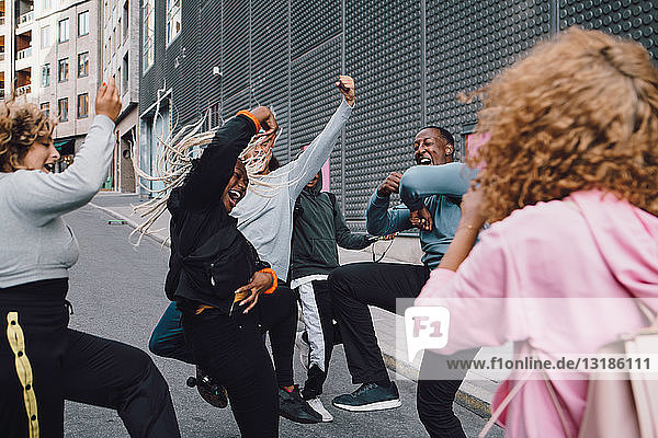 Glückliche Freunde tanzen auf der Straße mit einer Frau im Vordergrund