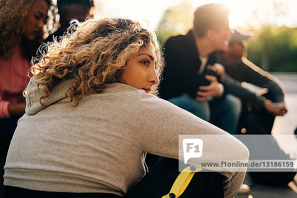 Nachdenkliche Frau sitzt mit Freunden im Skateboard-Park
