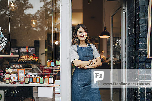 Portrait of confident female owner standing at entrance of deli