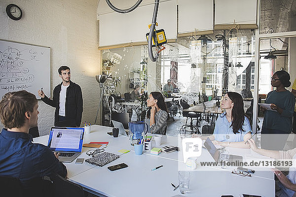 Creative businessman brainstorming colleagues during meeting in board room