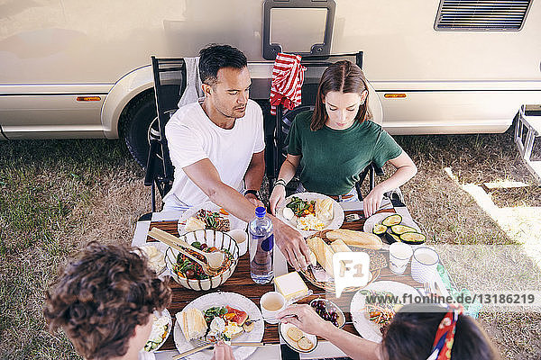 Schrägaufnahme von Eltern und Kindern  die auf dem Campingplatz am Tisch essen