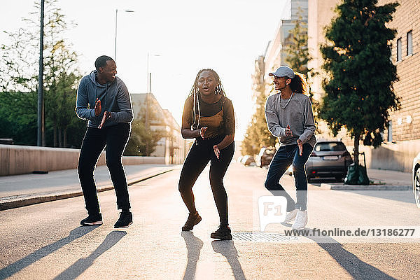 Teenager-Mädchen tanzt mit männlichen Freunden auf der Straße in der Stadt