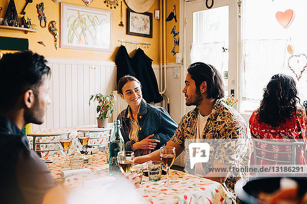 Lächelnde junge Frau mit männlichen Freunden  während sie im Restaurant am Tisch sitzt