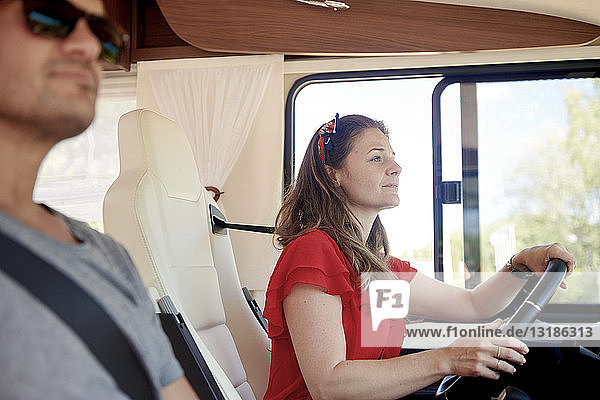 Woman driving while sitting with man in motor home